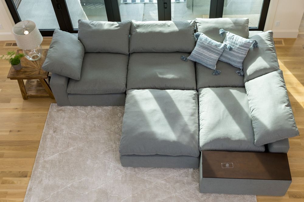 Top-down view of light gray modular sectional sofa with chaise lounge on neutral area rug.