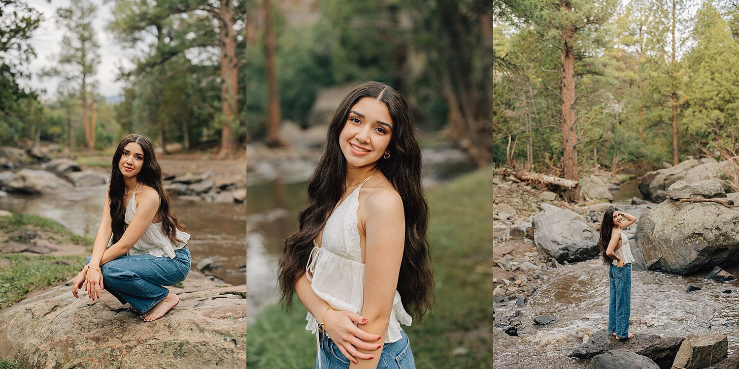 Young woman in jeans poses among forest rocks and trees in a nature portrait session.