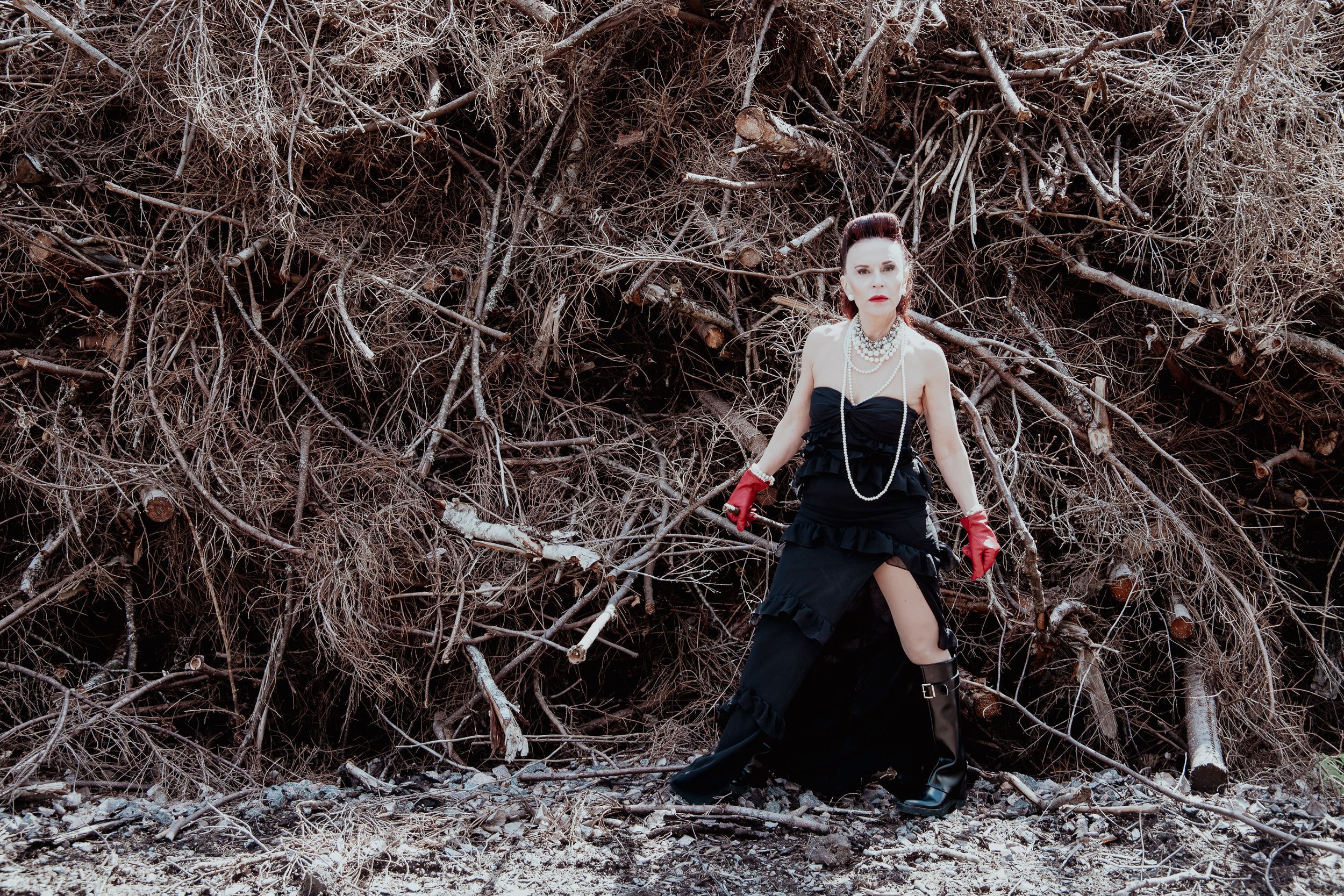 A woman in front of a pile of cut trees