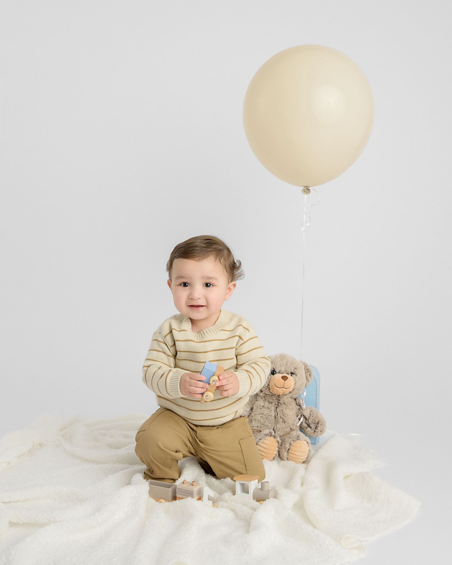 milestone portrait of a baby sitting on a soft cream set with a neutral balloon, photographed by a milestone Zephyrhills FL