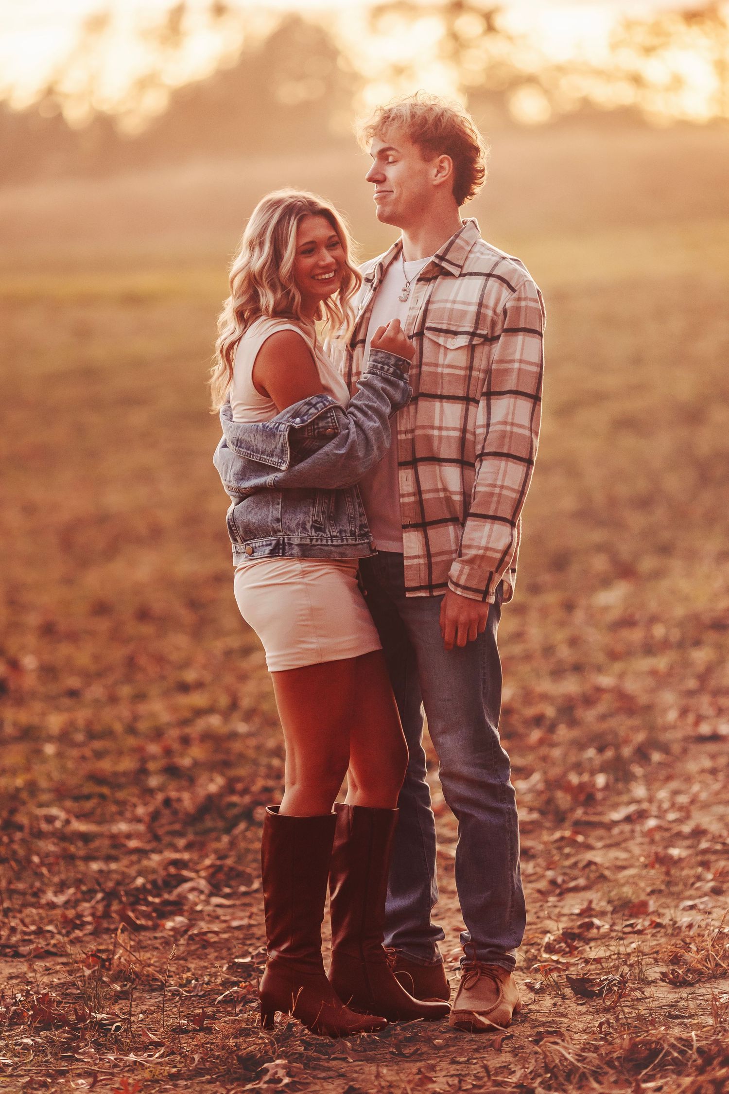 Couple sharing a romantic moment at golden hour, holding hands with an engagement ring visible.