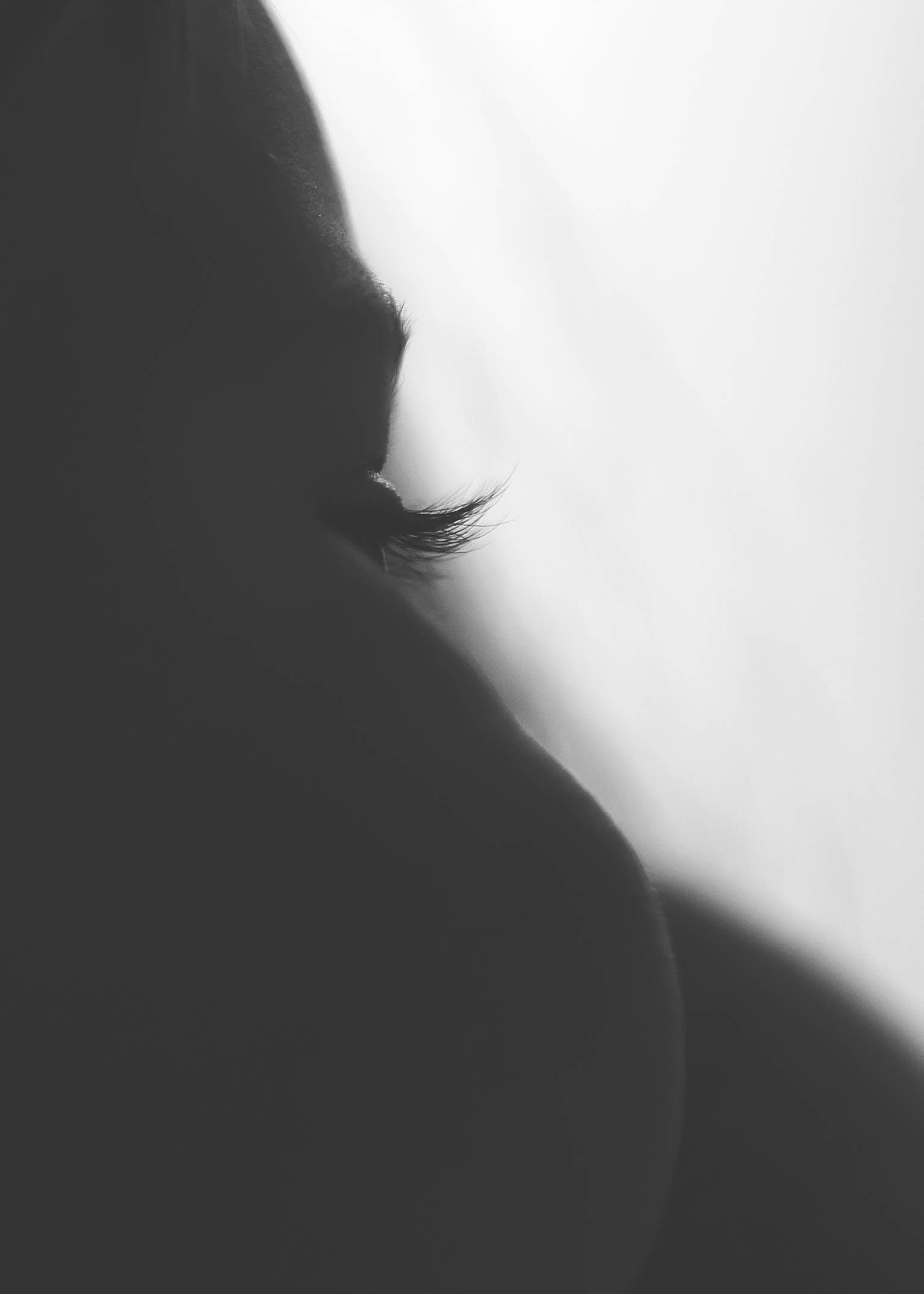 Artistic black and white silhouette portrait highlighting a person's eyelashes and profile.
