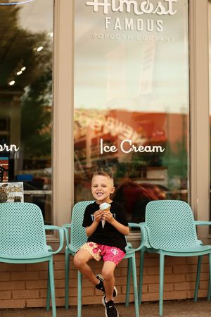 A happy young boy enjoys an ice cream cone outside Almost Famous Popcorn Company on a summer day.