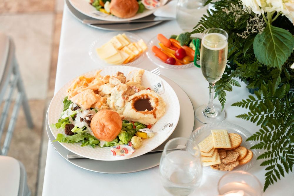 Elegant table setting with seafood plate, crackers, champagne, and tropical floral arrangement at a formal dining event.