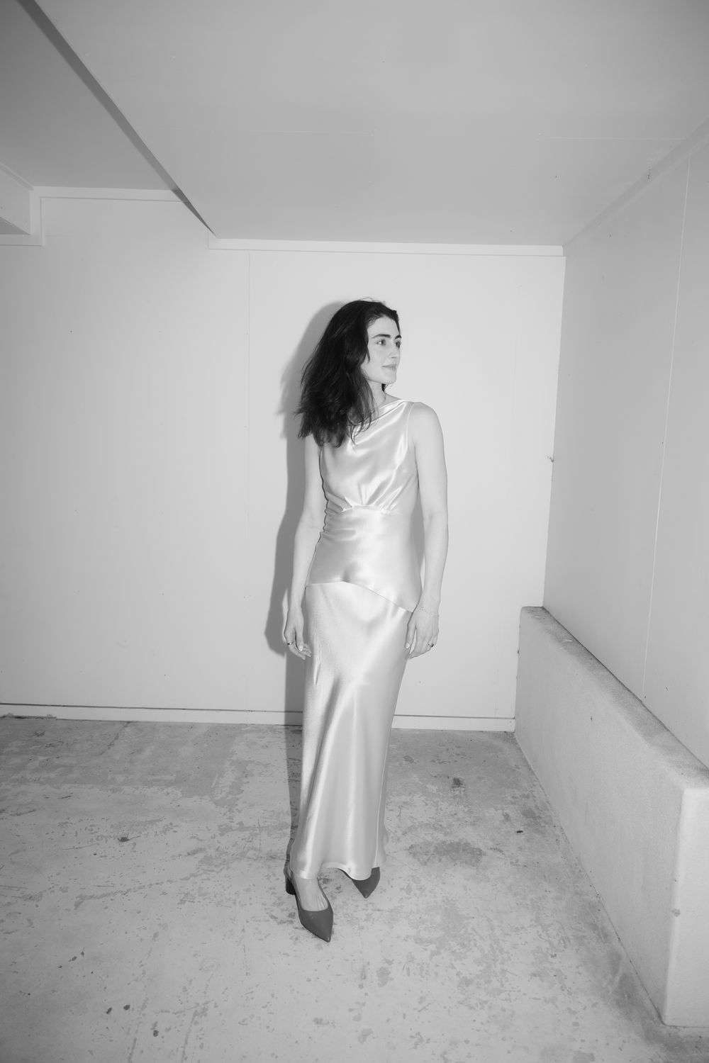 Model wearing elegant satin maxi slip dress in minimalist black and white fashion editorial.