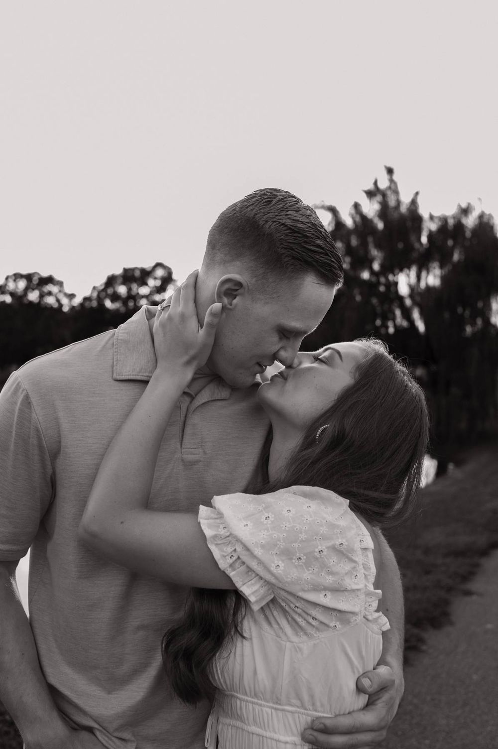 Black and white photo of couple sharing a passionate kiss outdoors near a pond, engagement photographer Mooresville NC