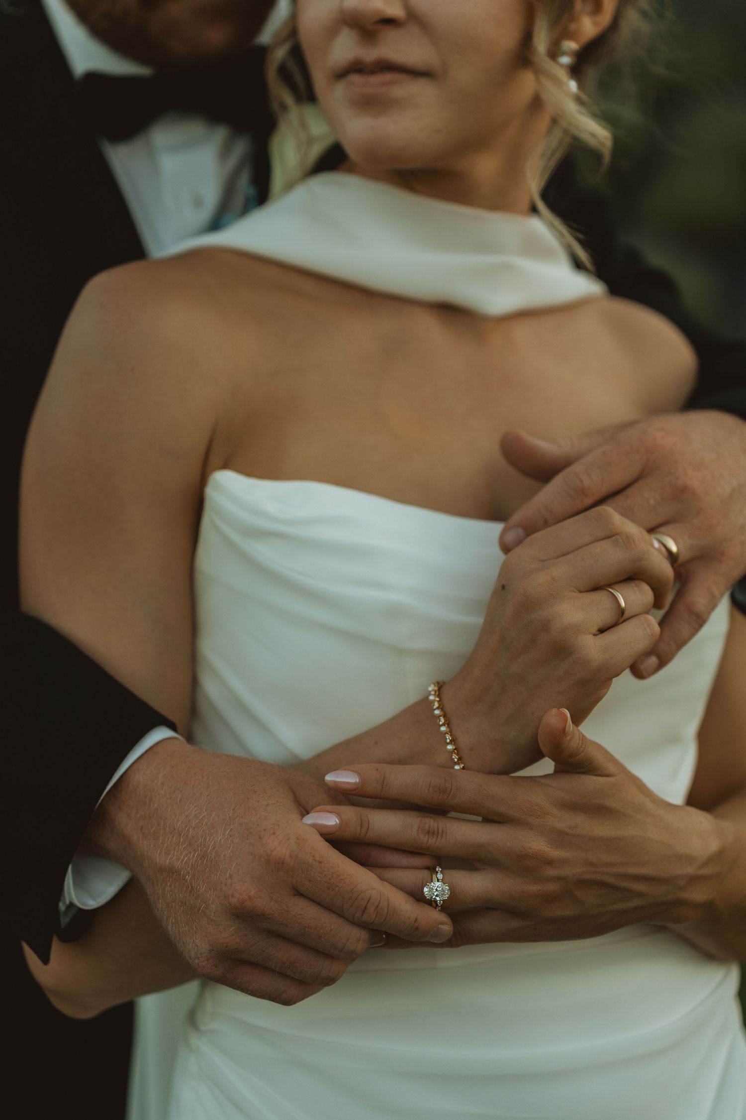 Wedding ring detail as the bride and groom hold hands