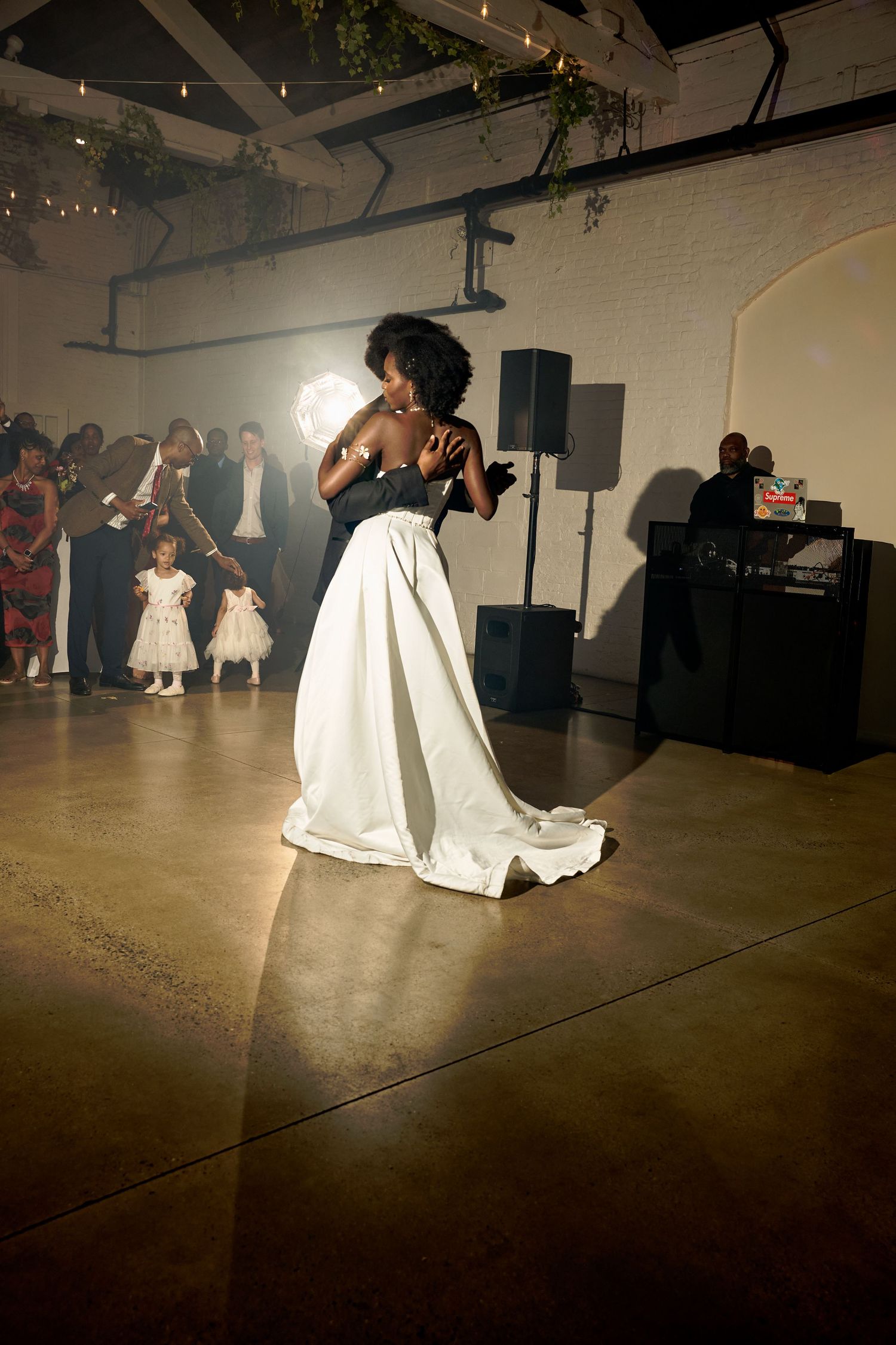 Bride in white gown dancing solo under spotlight at elegant wedding reception with guests watching.