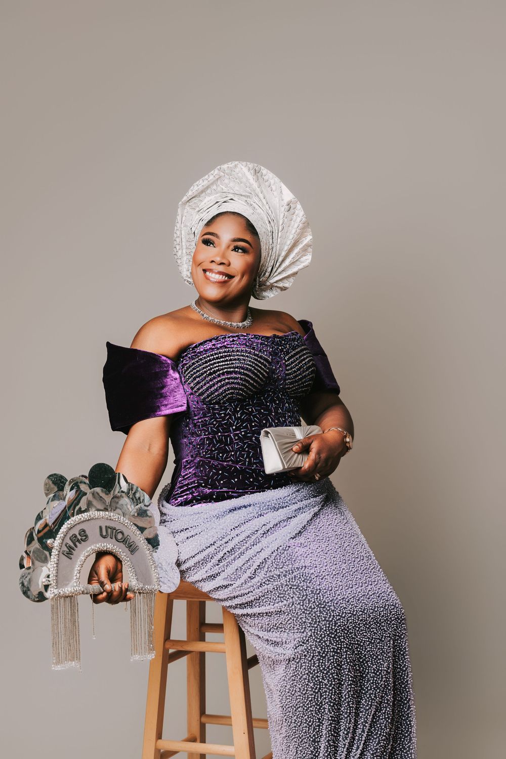 A smiling woman in traditional Nigerian attire with a gele headwrap, beaded purple gown, and sparkly skirt 40th Birthday Photoshoot Basildon