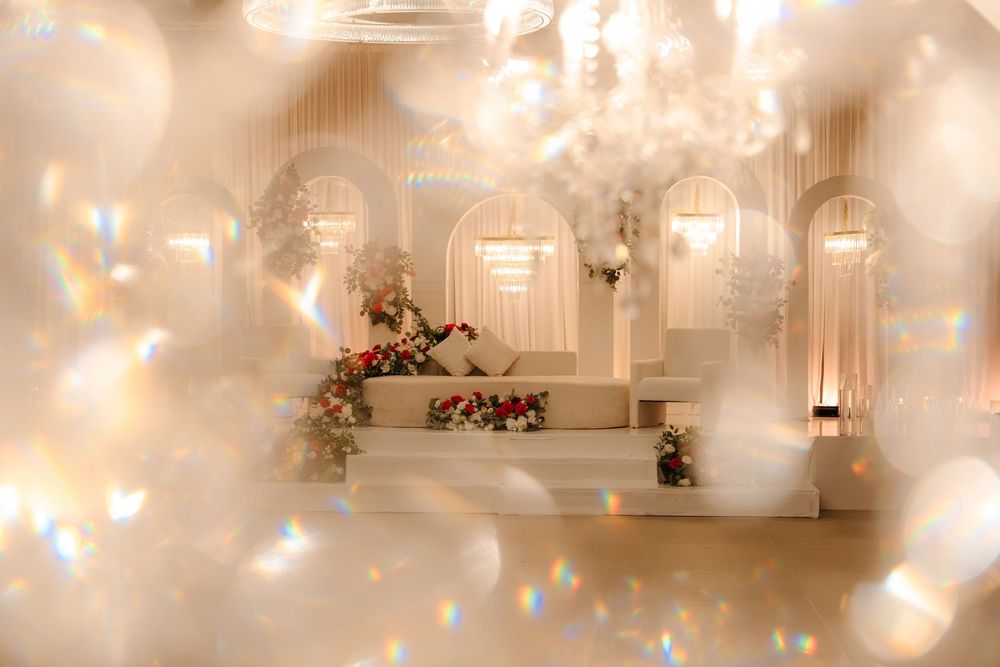 Elegant wedding venue with white arches, floral arrangements, and sparkling bokeh light effects creating a dreamy atmosphere.