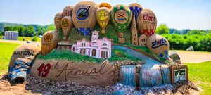 Colorful sand sculpture celebrating the 19th Annual event featuring hot air balloons and a castle centerpiece outdoors.