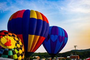 Colorful hot air balloons inflating at a festival against a blue sky at dusk.