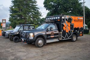 Wellsville branded Ford F-550 heavy-duty truck with off-road accessories parked on gravel lot with trees in background.