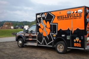 Wellsville Volunteer Ambulance Corps black and orange emergency vehicle unit 801 parked outdoors.