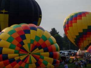 Colorful hot air balloons inflated at an outdoor balloon festival on a cloudy day.