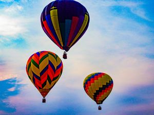 Three vibrant hot air balloons soaring against a colorful twilight sky with blue and purple hues.