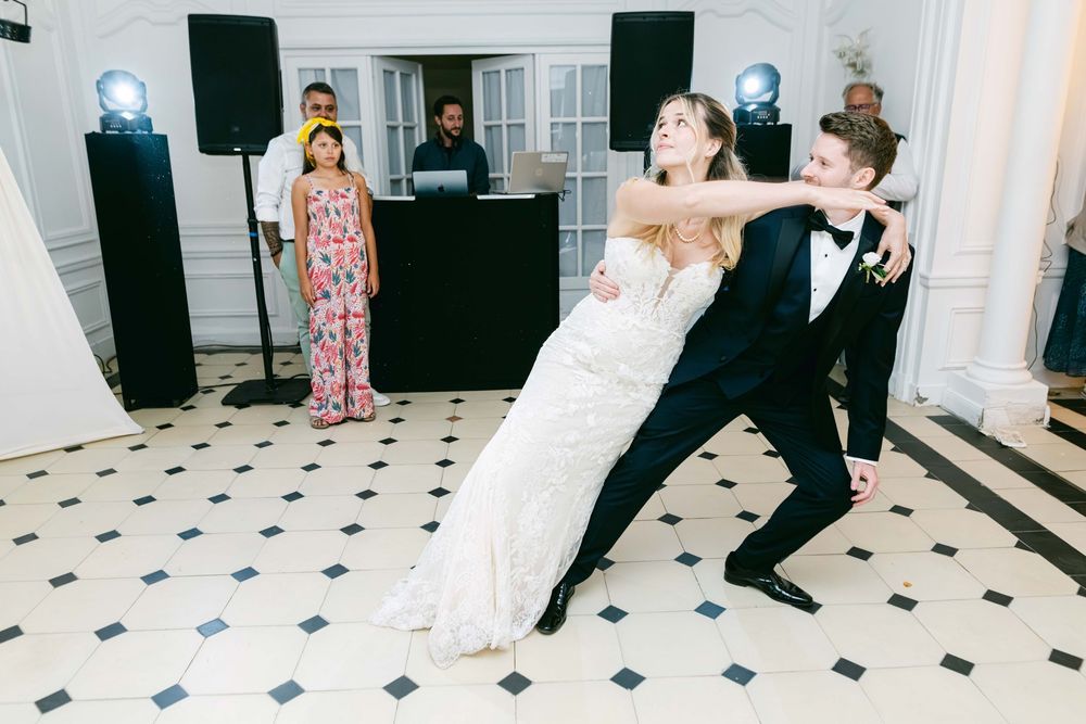 Bride and groom share a dramatic dip dance at their wedding reception on a black and white checkered dance floor.