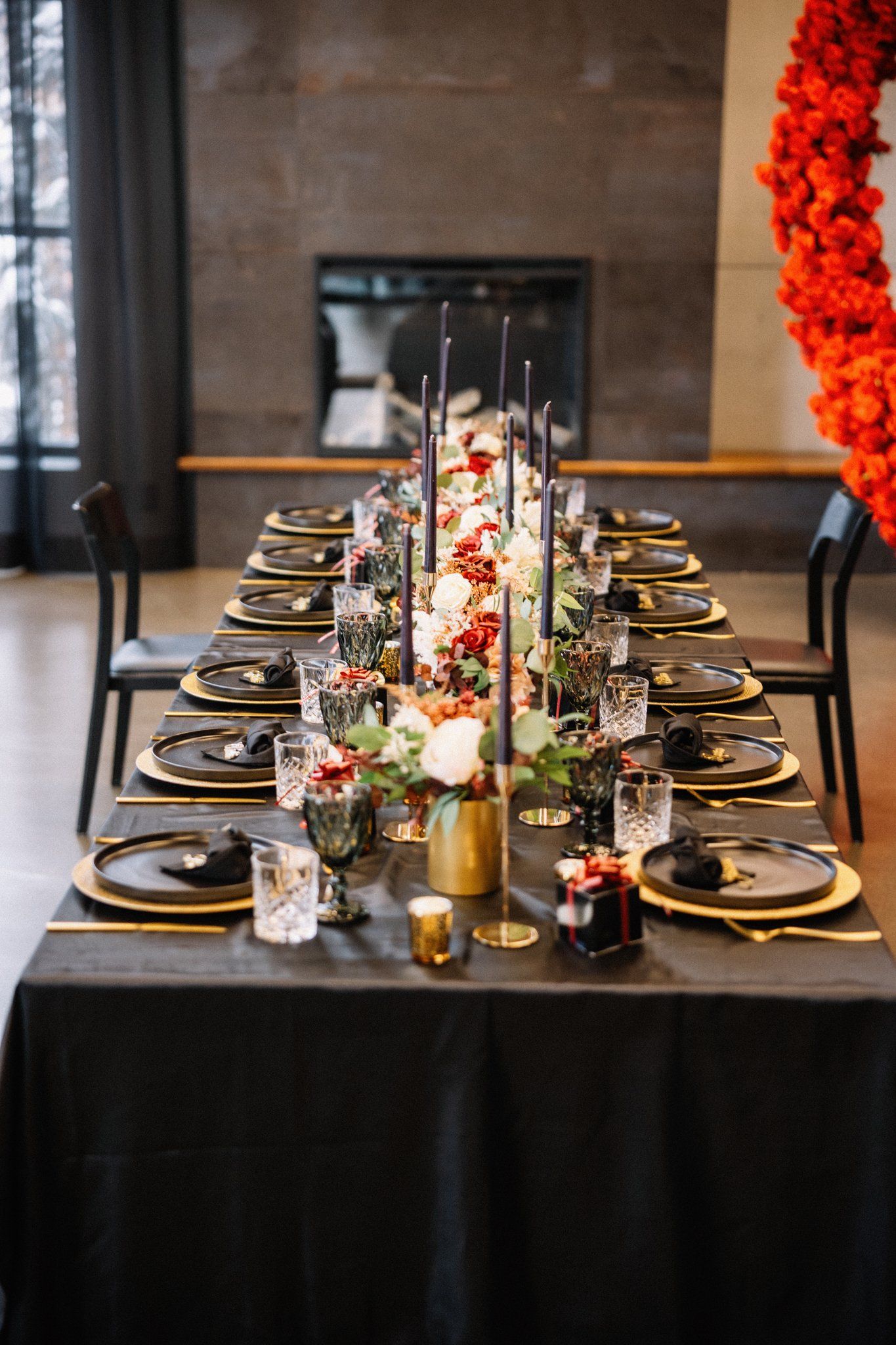 Black and gold wedding tablescape with crystal glasses, black candles and red and white florals at Mainspace