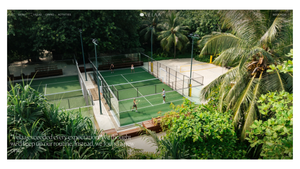 Aerial view of tropical resort padel tennis courts surrounded by lush palm trees and greenery.