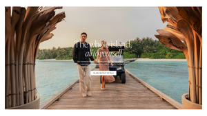 Couple walking on a tropical overwater pier with lush island backdrop and text reading The whole island, all to yourself.