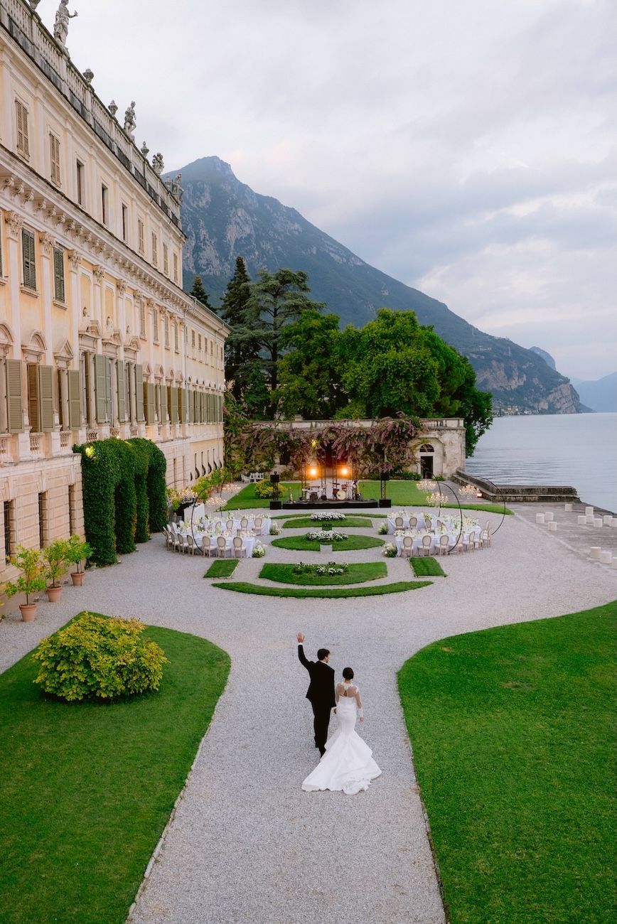 Bride and groom walking towards the reception in the lake view garden  of Villa Bettoni, Lake Garda. Italy. design by Solidea Events