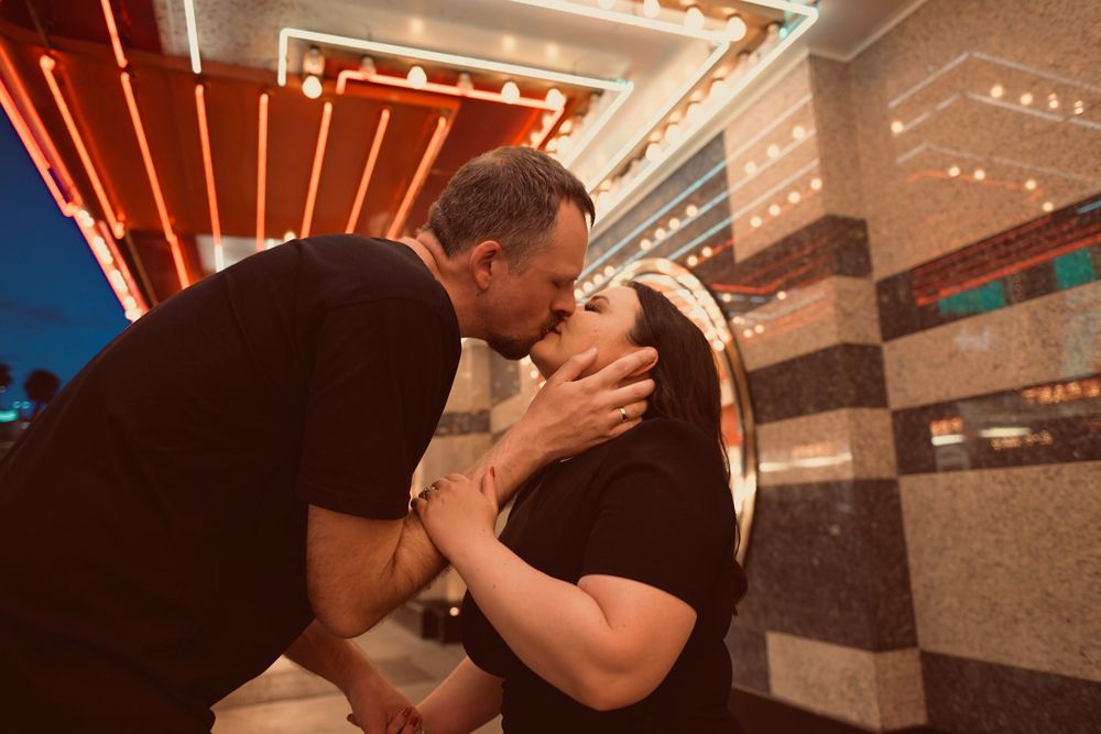Couple sharing a romantic kiss in front of neon lights at night in Las Vegas.