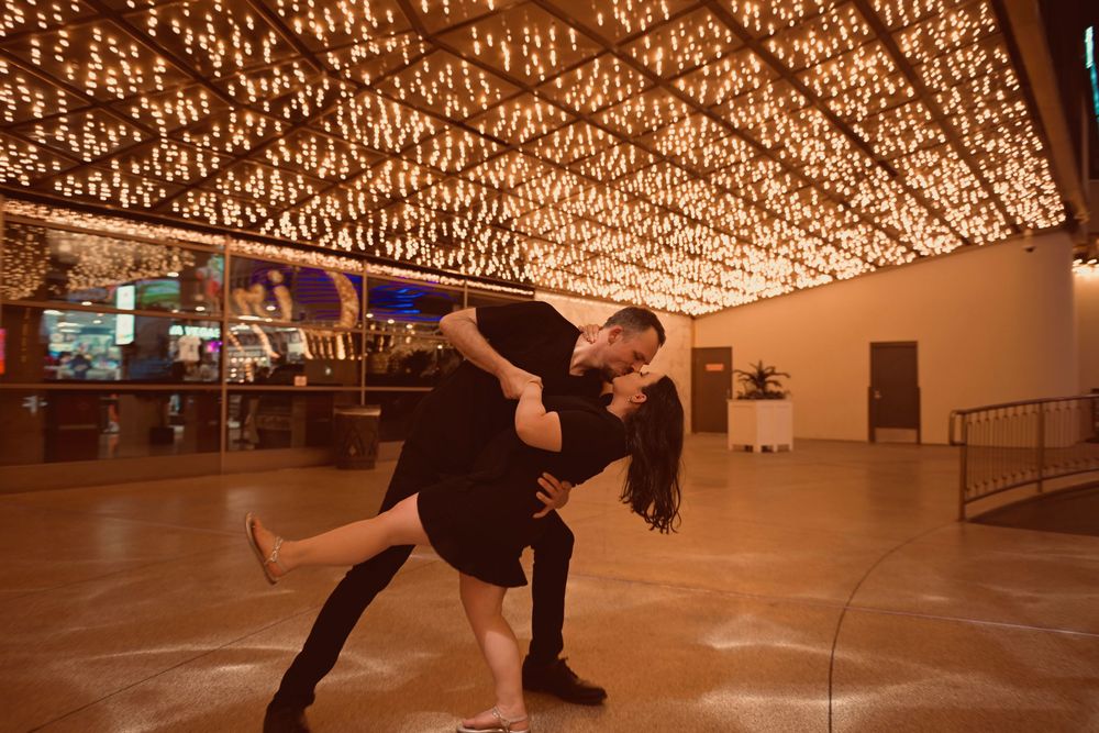 Couple performing a romantic dip dance move under a stunning golden lit ceiling in an elegant venue.