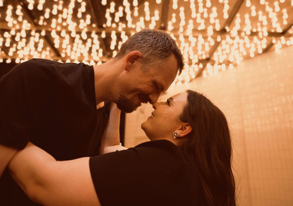 A romantic couple sharing an intimate moment under warm glowing fairy lights in a cozy ambiance.