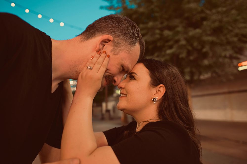 Loving couple touching foreheads and smiling intimately during a golden hour outdoor moment.