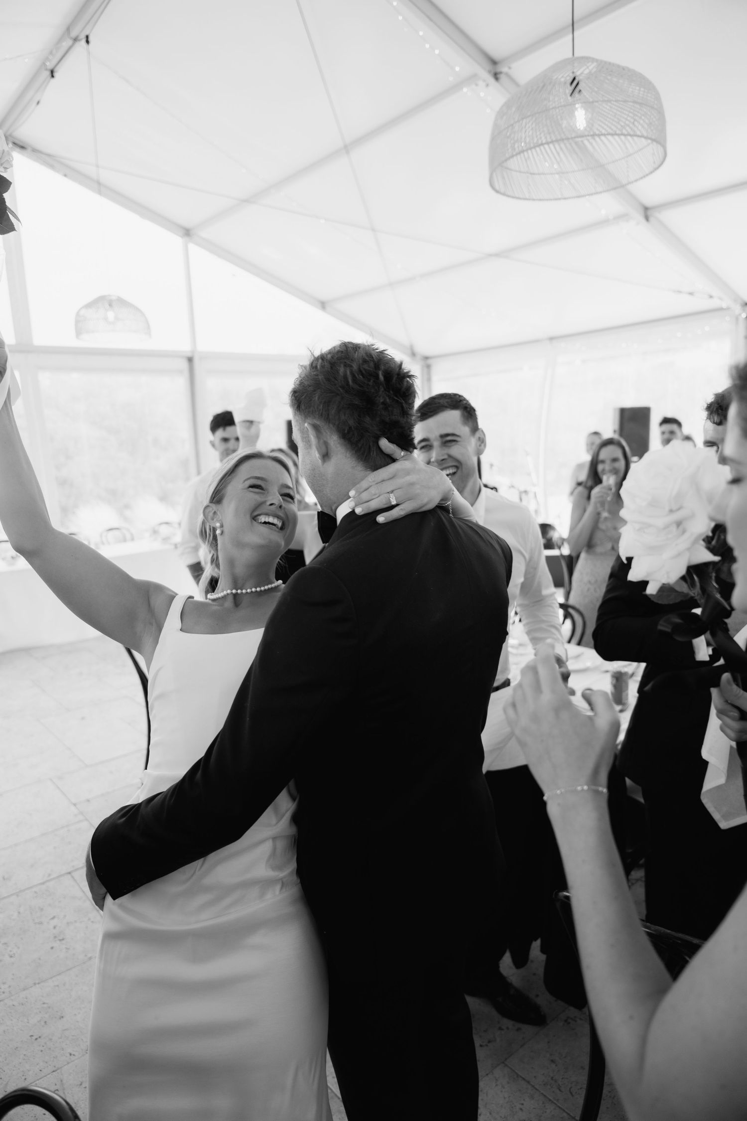 Black and white photo of a joyful bride and groom sharing their first dance at a wedding reception.