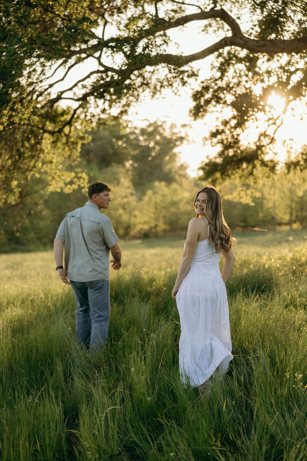 Couple walking through golden sunlit meadow during their engagement photos in Georgia.