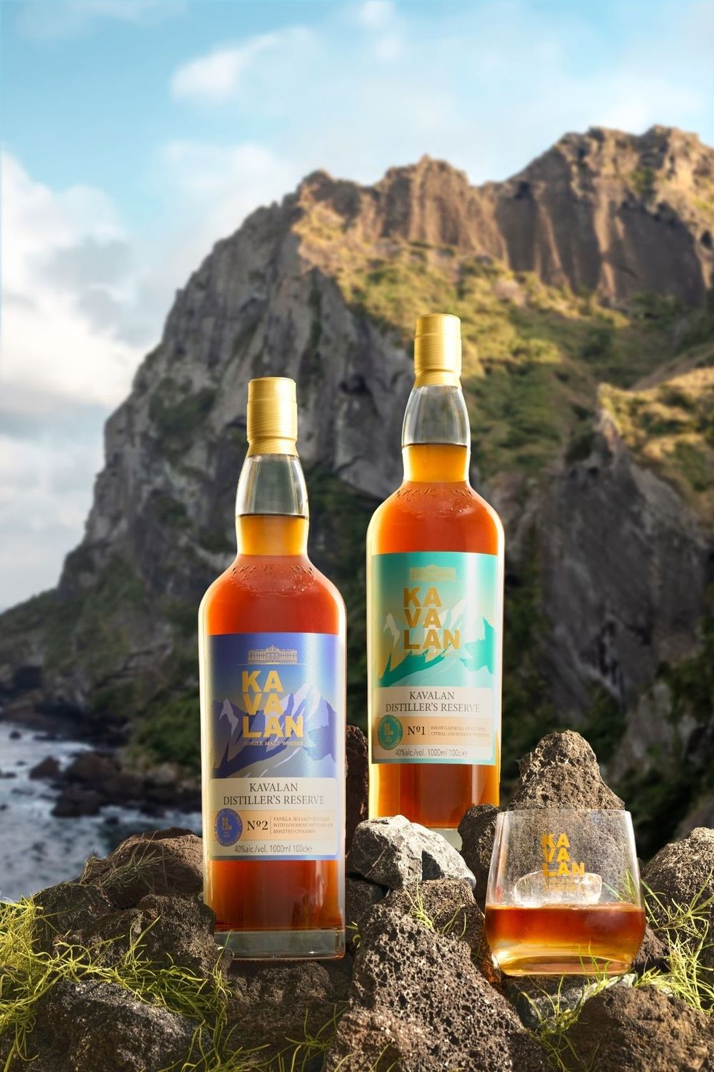 Two Kavalan Distiller's Reserve whisky bottles displayed on rocky coastline with dramatic cliffs and ocean backdrop.
