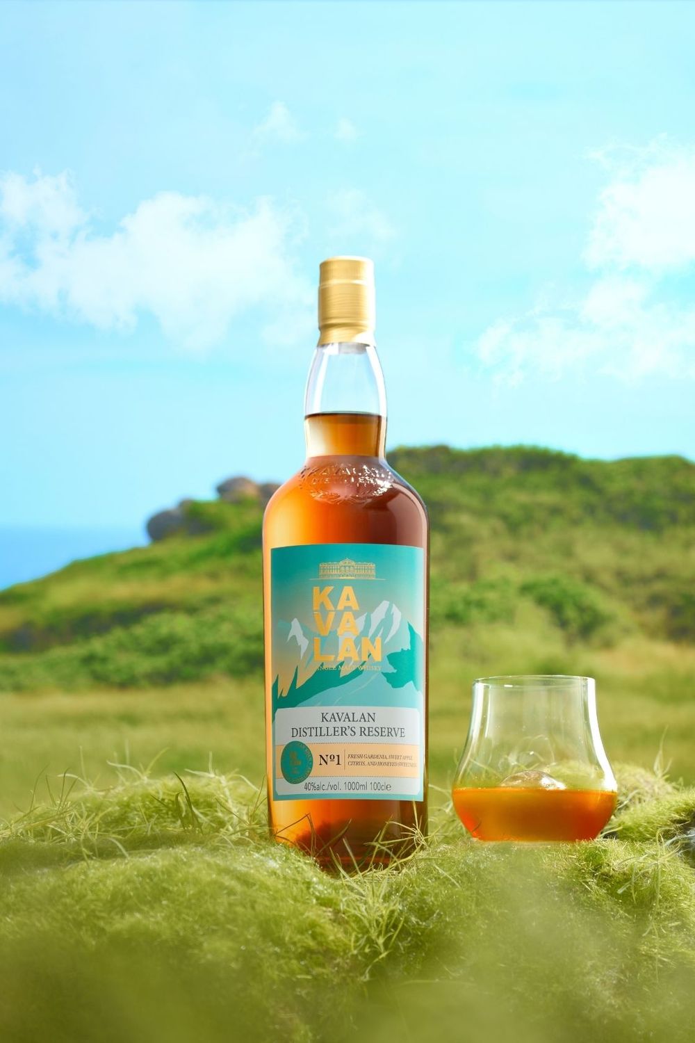 Kavalan Distiller's Reserve No.1 single malt whisky bottle with a glass on green grass under blue sky.