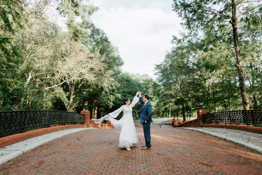 Bride and groom dancing on a brick path surrounded by lush green trees at an outdoor wedding venue.