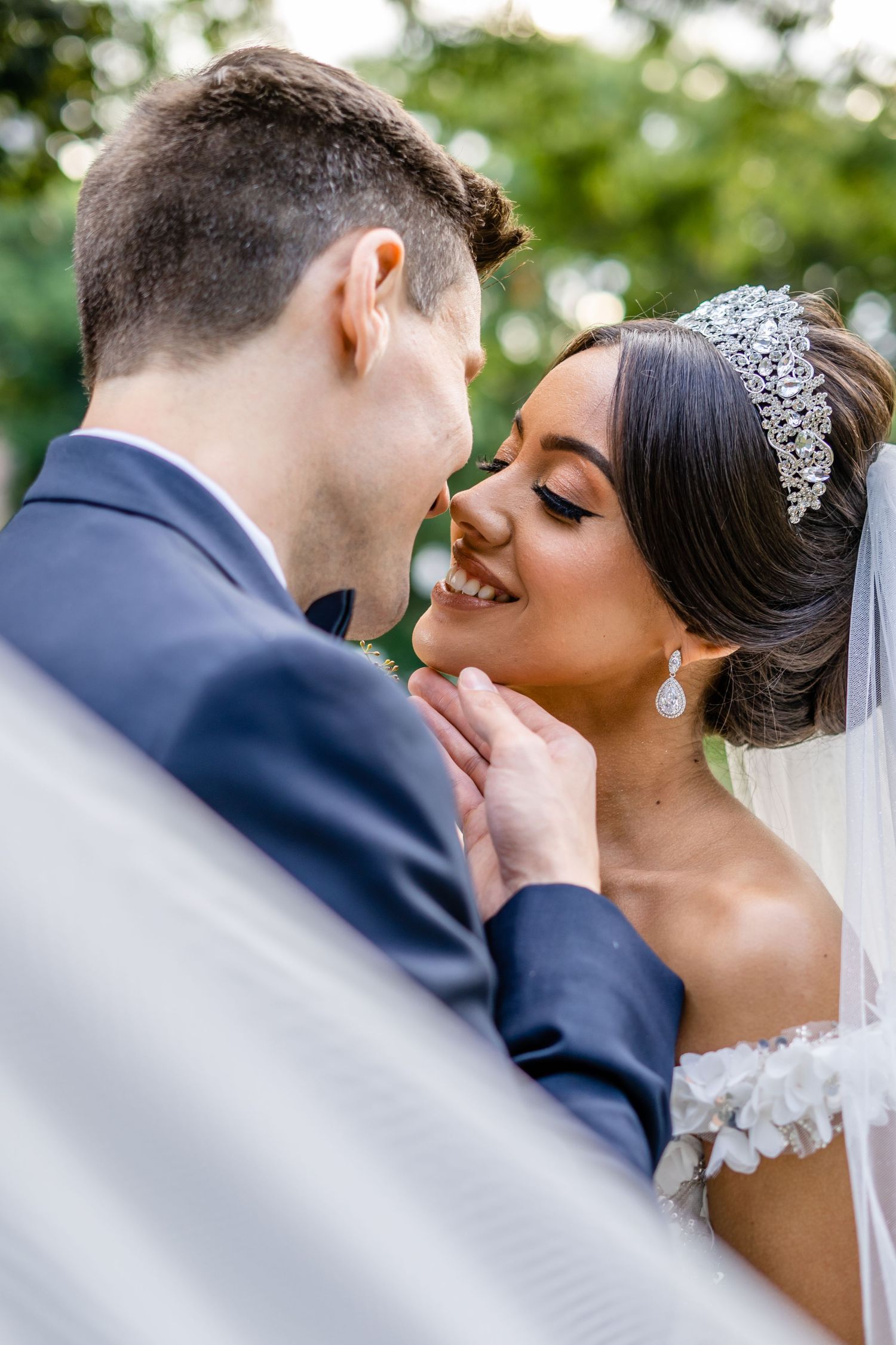 Close-up wedding portrait showing tender moment between couple with bride wearing crystal tiara and veil.