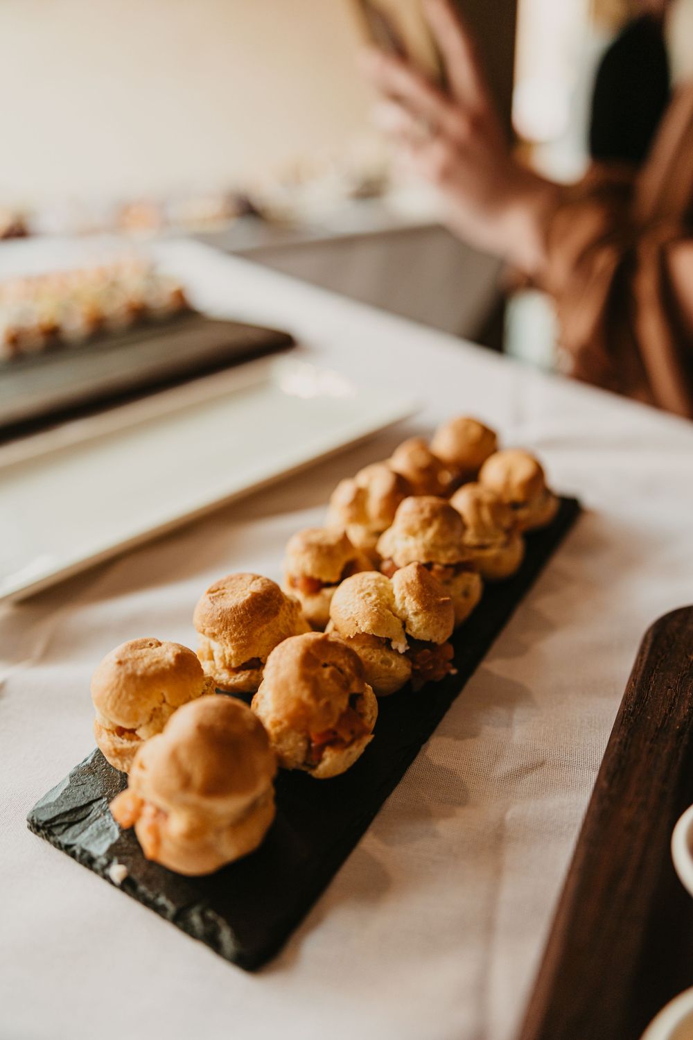 Elegant appetizer spoons with savory toppings arranged on a rustic wooden serving board at a catered event at 2nd Street Bistro Photographer