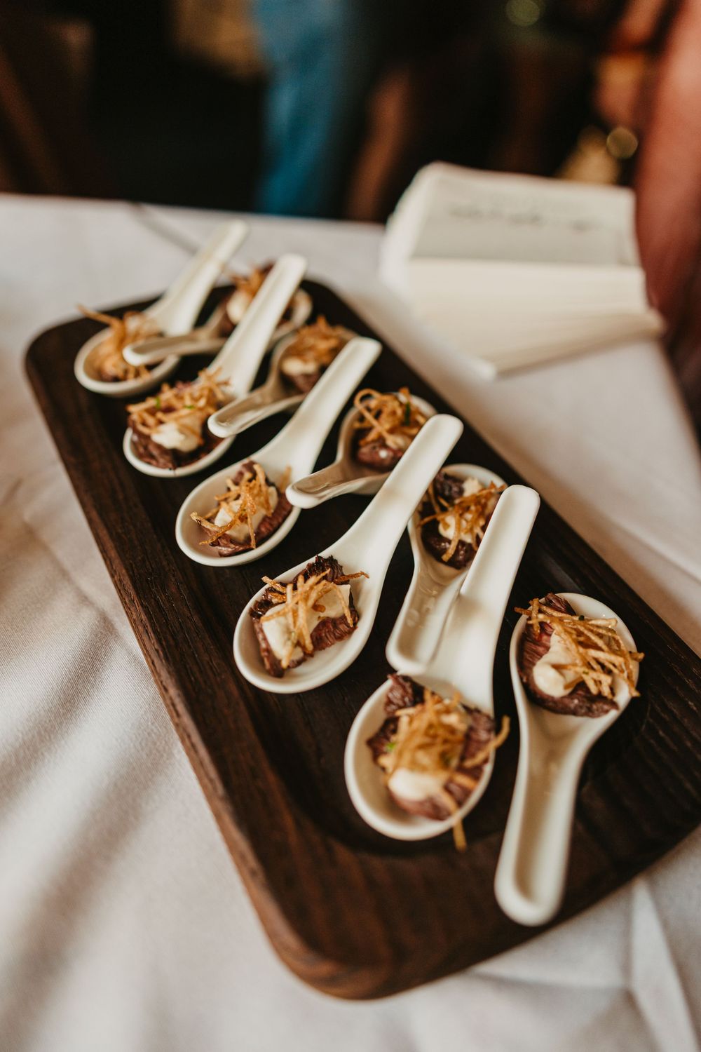 Elegant appetizer spoons with savory toppings arranged on a rustic wooden serving board at a catered event at 2nd Street Bistro Photographer