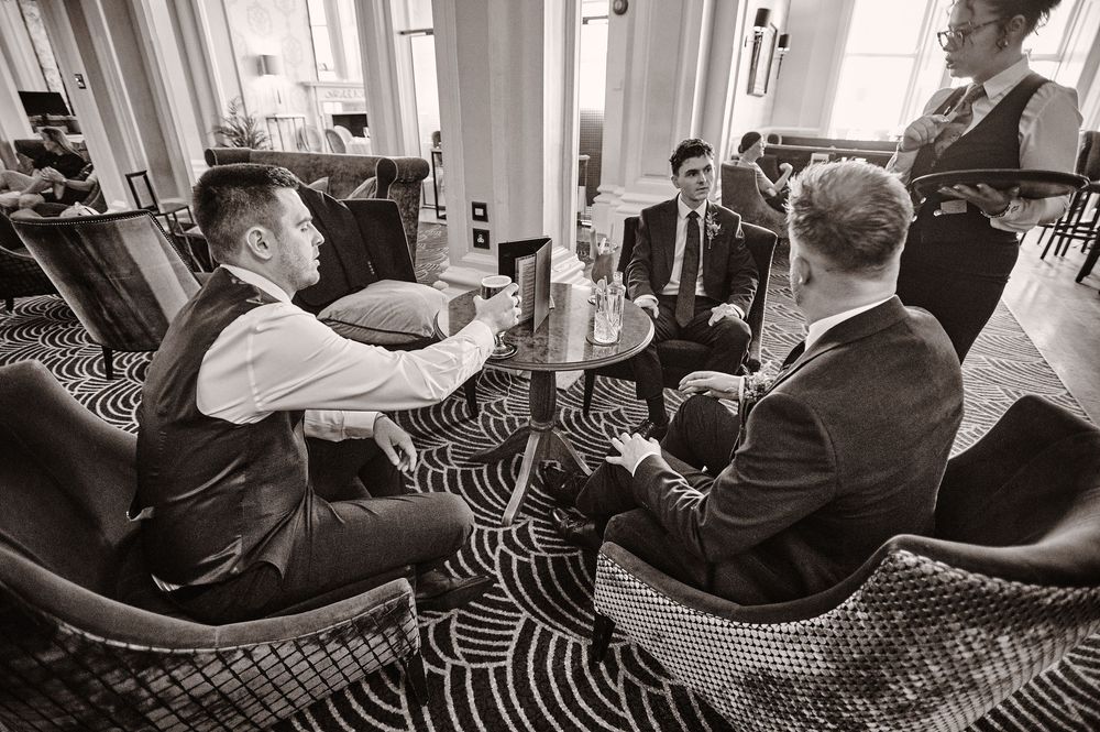 Groomsmen relax in stylish black and white lounge before wedding ceremony.