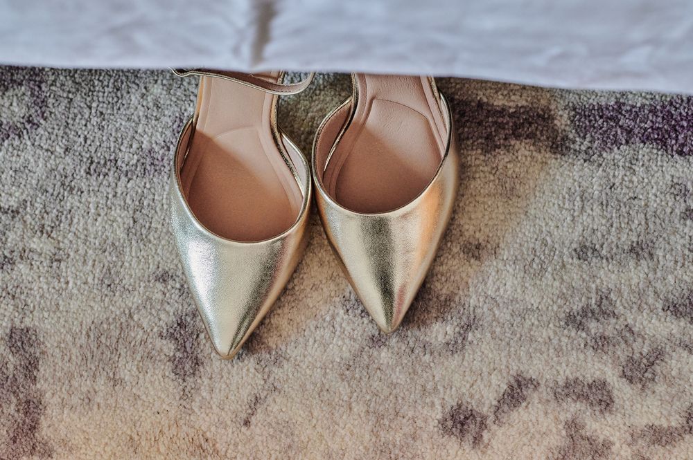 Gold pointed-toe slingback bridal heels placed on a textured carpet.