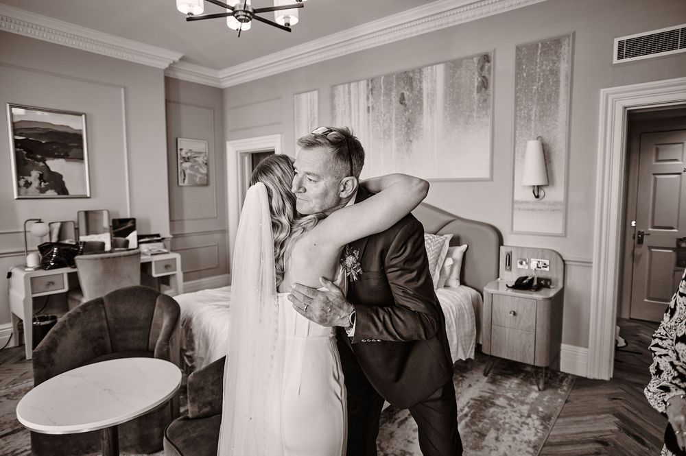 Bride and groom share an emotional first look embrace in an elegant hotel room on their wedding day.