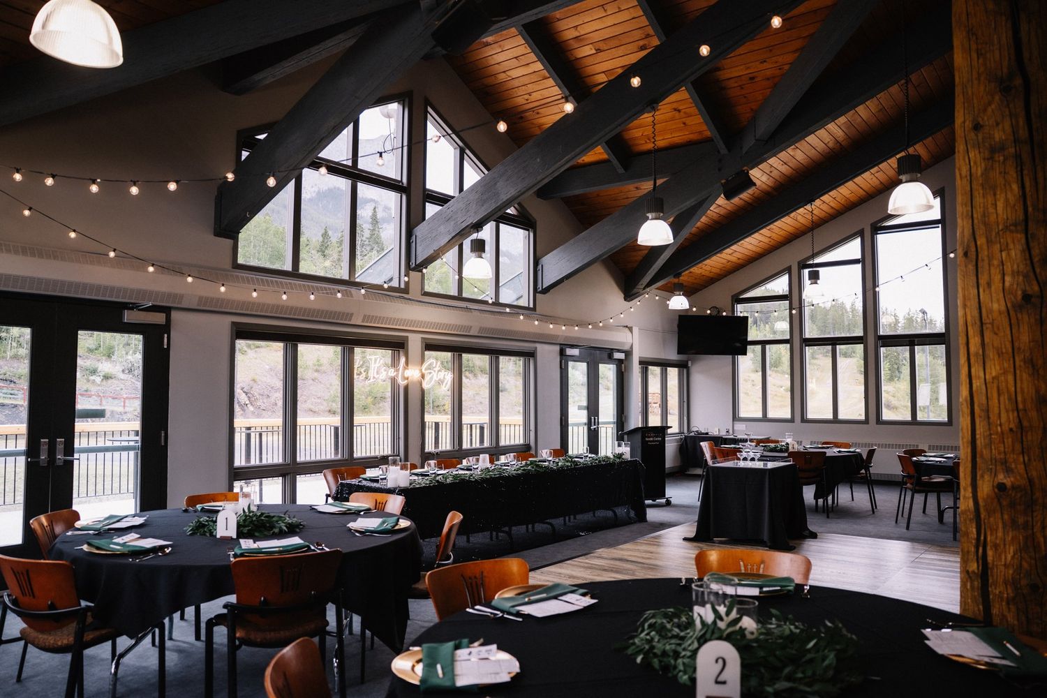 Empty Rundleview Room at the Canmore Nordic Centre Day Lodge set for a wedding reception, vaulted wood ceiling