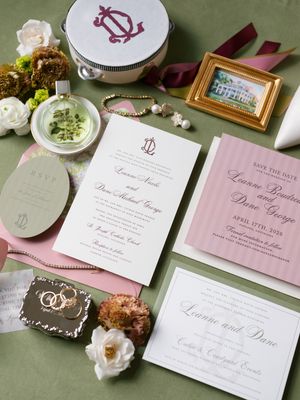Elegant wedding invitation suite with pink and white stationery on a green background.