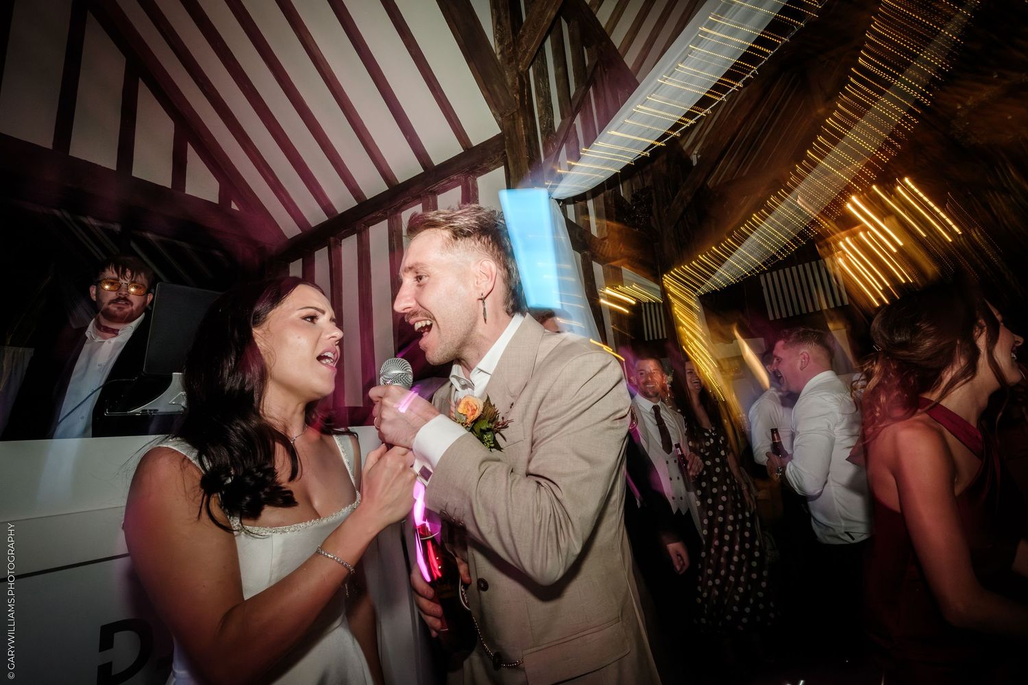 Bride and groom laughing and dancing joyfully together at their wedding reception in a rustic barn venue.