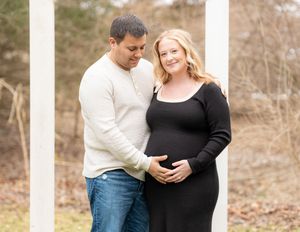 Couple embracing outdoors, man tenderly touching pregnant womans belly.