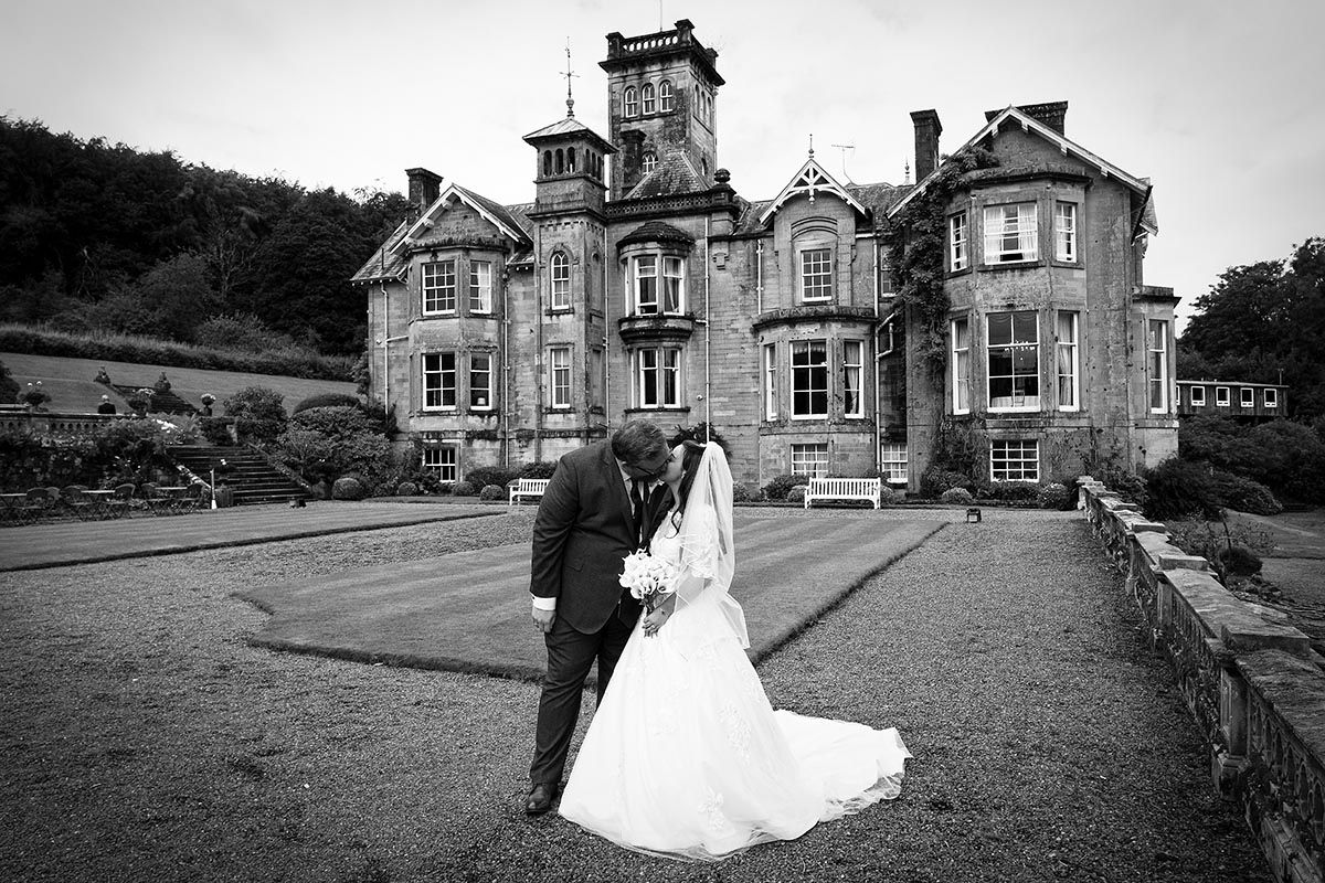 Black and white portrait of newlyweds kissing outside Auchen Castle