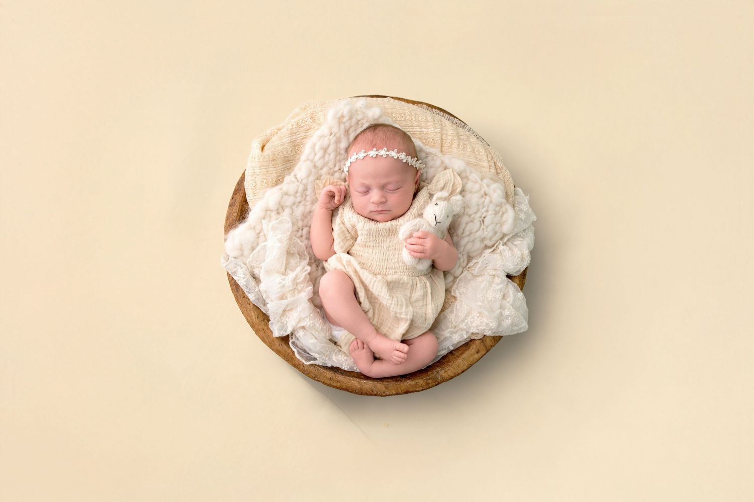 Smiling pregnant woman in sheer peach tulle robe posing against a soft yellow background, showcasing her baby bump.
