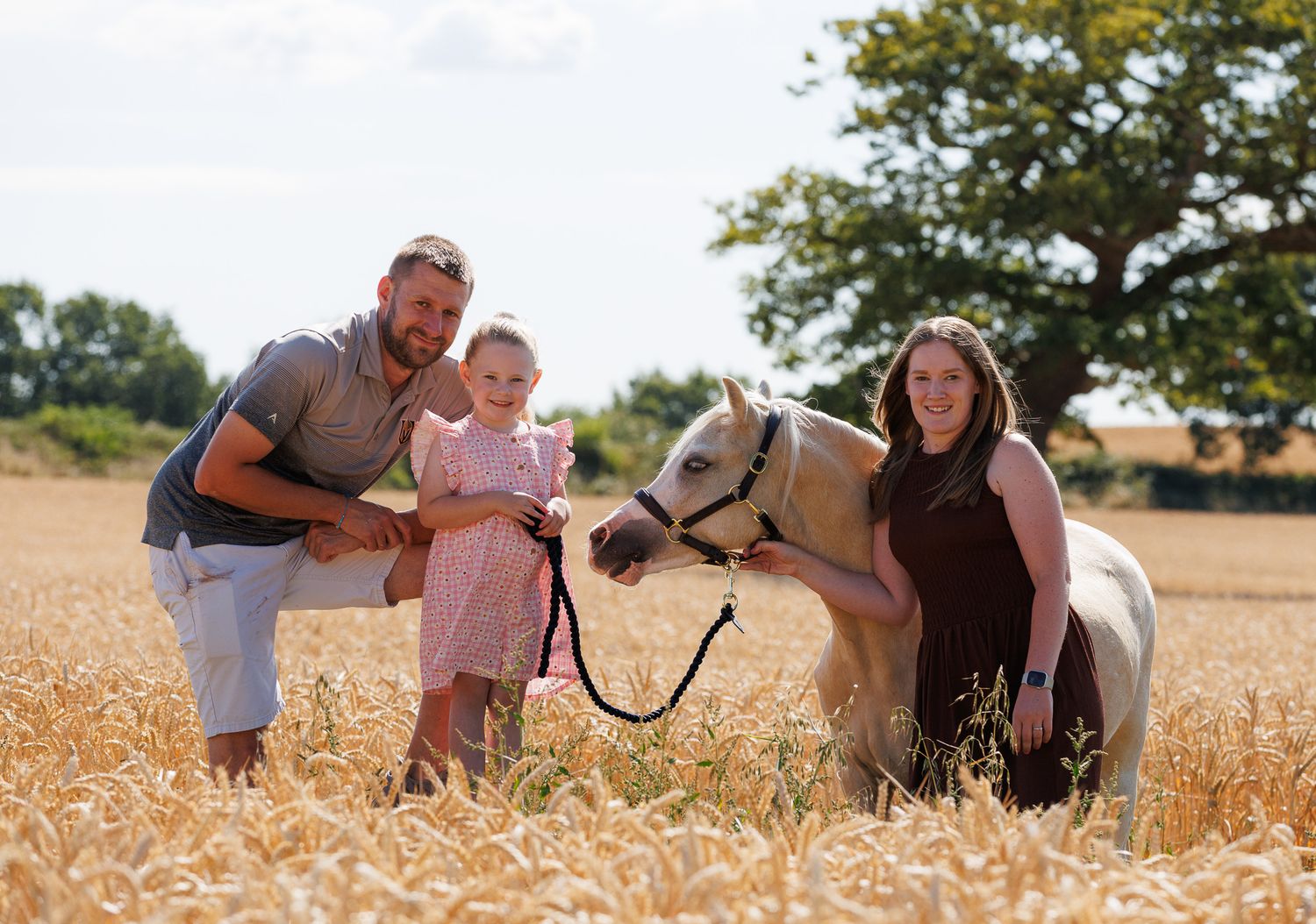 A horse and its rider enjoy an outdoor photoshoot session near rustic wooden fencing on a sunny day.