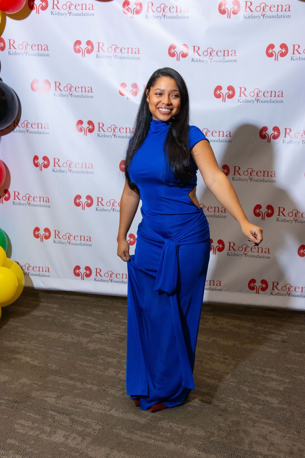 Woman in royal blue gown posing at Roeena Kidney Foundation event backdrop.