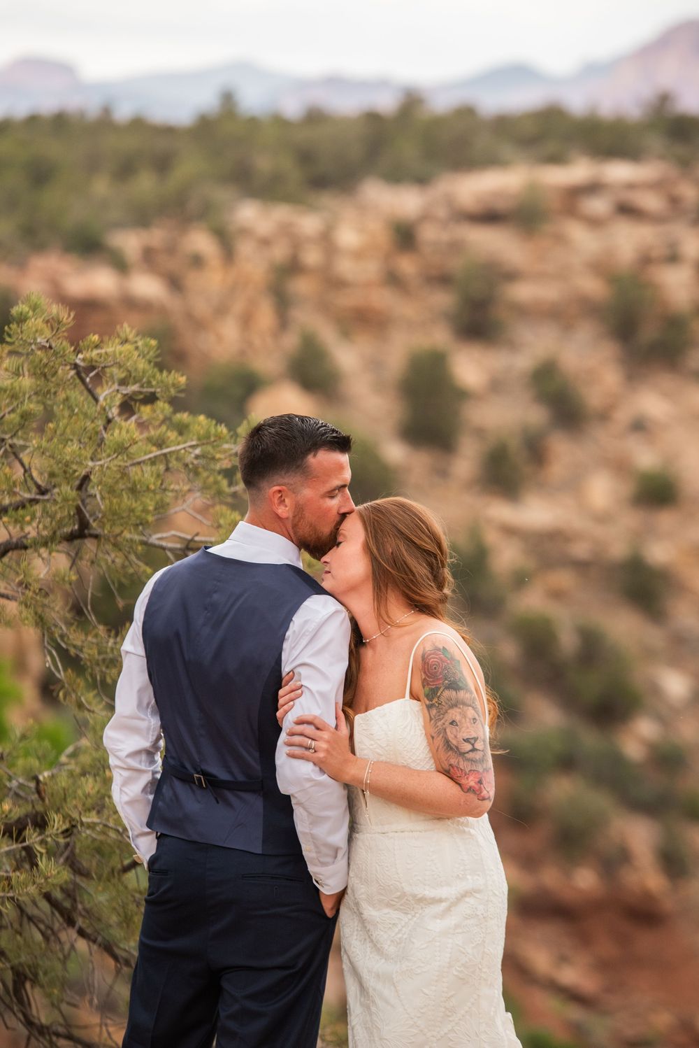 Bride and groom share a kiss with stunning red rock canyon scenery in the background.