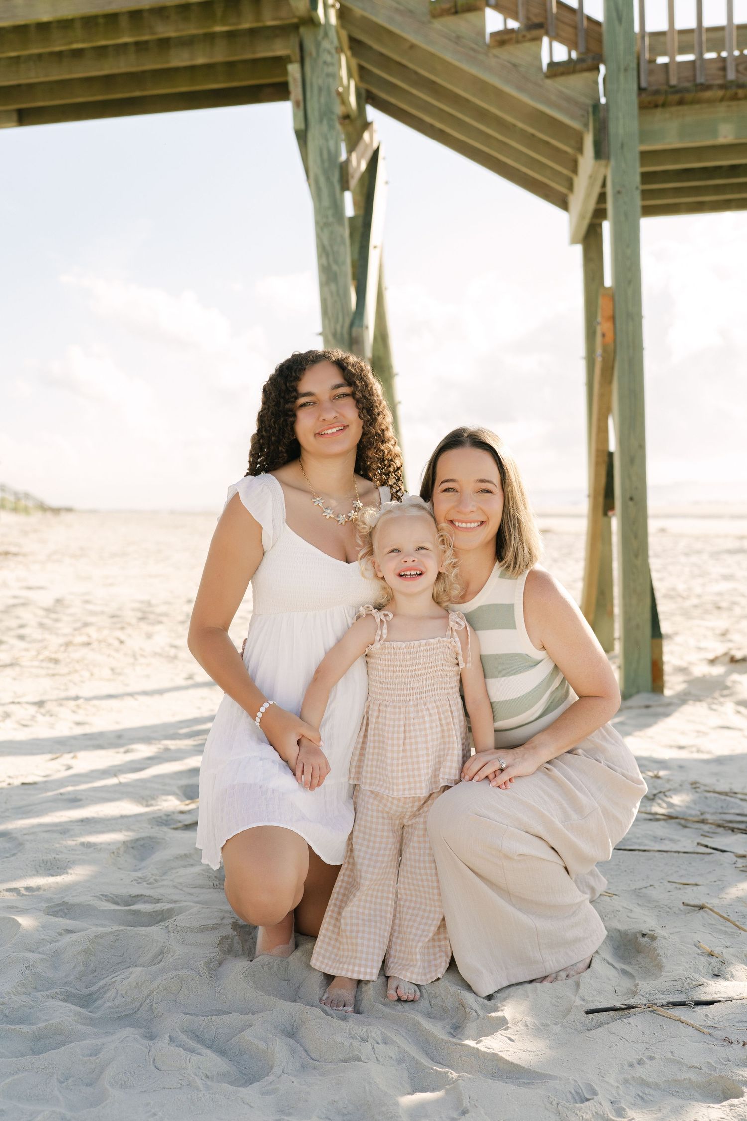 Mother and two daughters together during a family beach portrait session on Jekyll Island. High sun beach session in the middle of the day